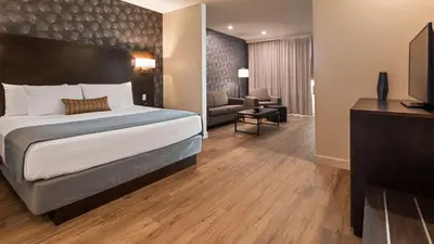 a bedroom with a large bed and a living room at Best Western Plus Montreal East in Montréal