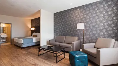 a hotel room with a couch and a bed at Best Western Plus Montreal East in Montréal