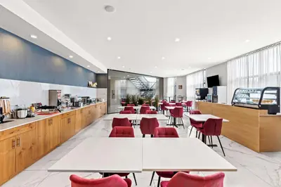 a restaurant with white tables and red chairs at Best Western Plus Montreal East in Montréal
