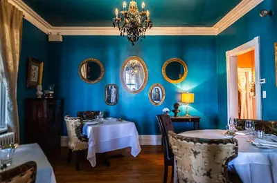 a dining room with two tables and a chandelier at Manoir Becancourt Hotel in Bécancour