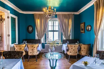 a dining room with blue walls and a table and chairs at Manoir Becancourt Hotel in Bécancour