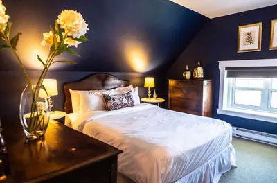 a bedroom with a bed and a vase of flowers on a table at Manoir Becancourt Hotel in Bécancour