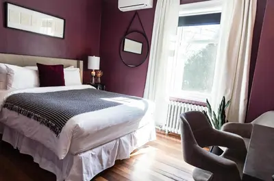 a bedroom with purple walls and a bed and a chair at Manoir Becancourt Hotel in Bécancour