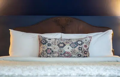 a bed with a pillow and a wooden headboard at Manoir Becancourt Hotel in Bécancour