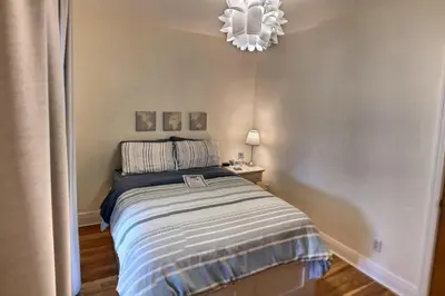 a small bedroom with a bed and a chandelier at Gite du Survenant Montreal in Montréal