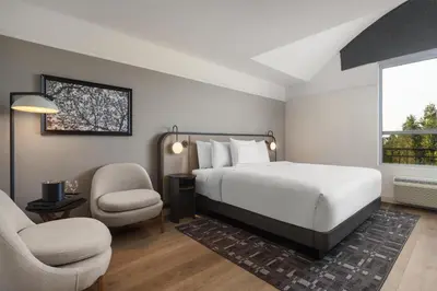 a bedroom with a bed and a chair and a window at Hotel Vallea Bromont, Tapestry Collection by Hilton in Bromont