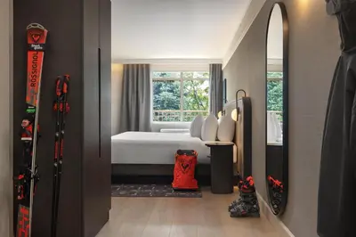 a bedroom with a bed and a window and a mirror at Hotel Vallea Bromont, Tapestry Collection by Hilton in Bromont