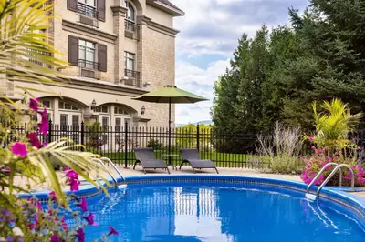 a swimming pool with chairs and an umbrella in front of a building at Hotel Vallea Bromont, Tapestry Collection by Hilton in Bromont