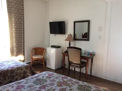 a room with a bed and a desk and a television at Hotel Bon Accueil in Montréal