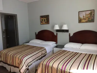 two beds in a hotel room with white walls at Hotel Bon Accueil in Montréal