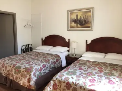 a hotel room with two beds and a picture on the wall at Hotel Bon Accueil in Montréal
