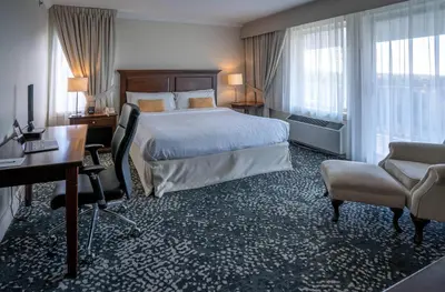 a hotel room with a large bed and a desk and a desk at Manoir Des Sables, an Ascend Collection Hotel in Magog-Orford