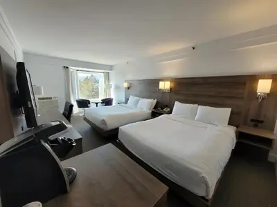 a hotel room with two beds and a television at Manoir Des Sables, an Ascend Collection Hotel in Magog-Orford