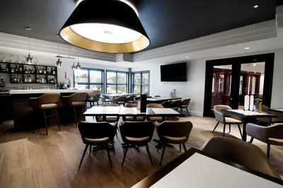 a restaurant with tables and chairs and a bar at Manoir Des Sables, an Ascend Collection Hotel in Magog-Orford