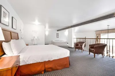 a hotel room with a bed and a desk and chairs at Hotel Le Victorin, an Ascend Hotel Collection Member in Victoriaville