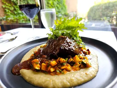 a plate of food with meat and vegetables on a table at Hotel Le Victorin, an Ascend Hotel Collection Member in Victoriaville