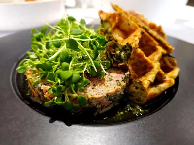 a plate of food with waffles and a salad at Hotel Le Victorin, an Ascend Hotel Collection Member in Victoriaville
