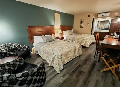 a hotel room with two beds and a desk at Hotel-Motel Drummond in Drummondville