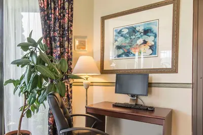 a room with a desk with a computer and a plant at Quality Hotel & Suites in Sherbrooke