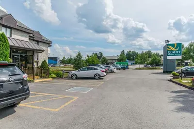 a parking lot with cars parked in front of a car dealership at Quality Hotel & Suites in Sherbrooke