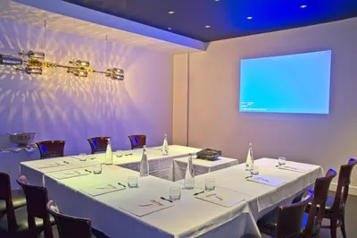 a conference room with two tables and a projection screen at Hotel Chez Swann in Montréal