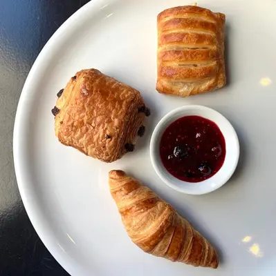 a white plate with croissants and a bowl of jam at Hotel Chez Swann in Montréal