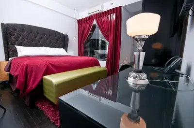 a bedroom with a bed with a red blanket and a phone at Hotel Chez Swann in Montréal