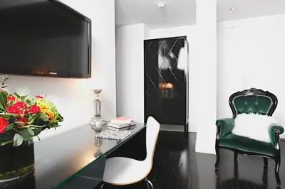 a living room with a desk with a tv and a chair at Hotel Chez Swann in Montréal