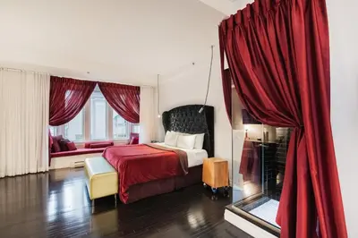 a bedroom with a bed and a red curtain at Hotel Chez Swann in Montréal