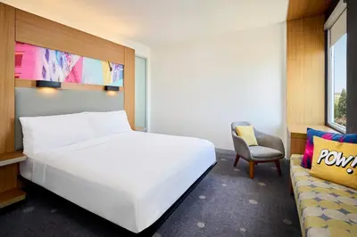 a bedroom with a large white bed and a chair at Aloft Montreal Airport in Dorval