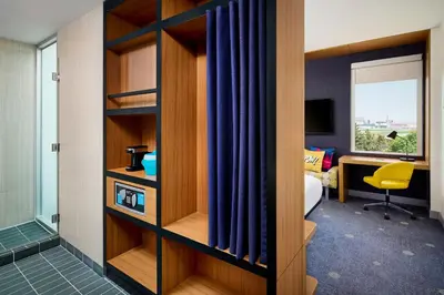 a hotel room with ajar partition with blue curtains at Aloft Montreal Airport in Dorval