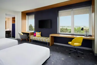 a hotel room with a bed and a desk with a computer at Aloft Montreal Airport in Dorval