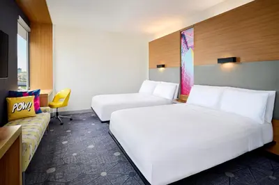a hotel room with two beds and a couch at Aloft Montreal Airport in Dorval