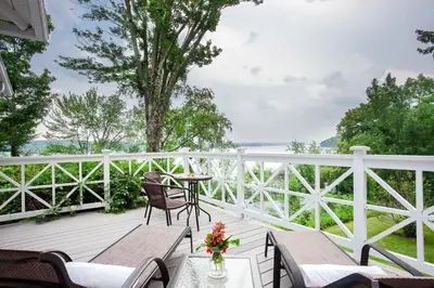 a porch with chairs and tables and a fence at Manoir Hovey, Relais & Châteaux in North Hatley