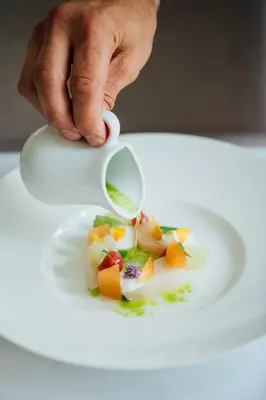 a hand holding a spoon over a plate of food at Manoir Hovey, Relais & Châteaux in North Hatley