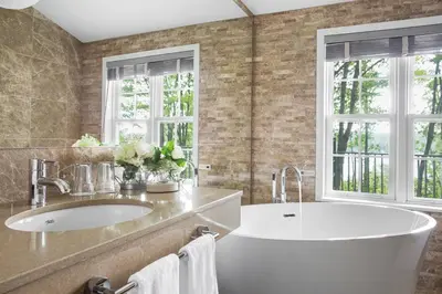 a bathroom with a tub and a sink and two windows at Manoir Hovey, Relais & Châteaux in North Hatley