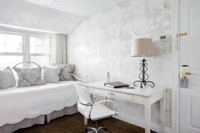 a bedroom with a bed with a desk and a chair at Manoir Hovey, Relais & Châteaux in North Hatley