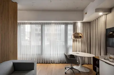 a living room with a desk and a couch and a window at Hôtel Le Germain Montréal in Montréal