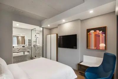 a bedroom with a white bed and a blue chair at Hôtel Le Germain Montréal in Montréal