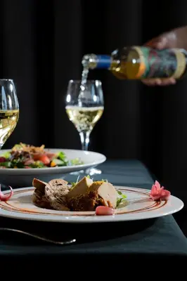 a person pouring white wine into two plates of food at Auberge Godefroy in Bécancour