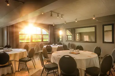 a room with tables and chairs and a mirror at Auberge Godefroy in Bécancour