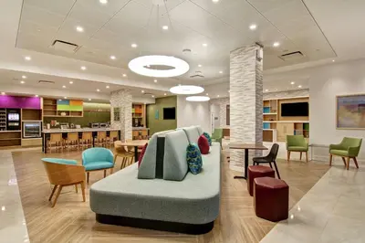 a lobby with a couch and tables and chairs at Home2 Suites By Hilton Montreal Dorval in Dorval