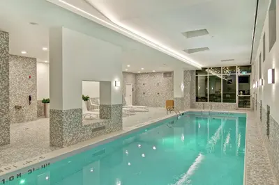 a large swimming pool with blue water in a building at Home2 Suites By Hilton Montreal Dorval in Dorval