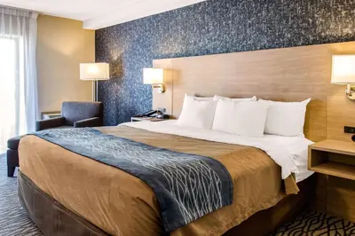 a hotel room with a large bed and a chair at Comfort Inn Aeroport in Dorval