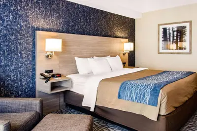 a hotel room with a large bed and two chairs at Comfort Inn Aeroport in Dorval