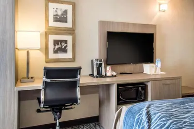 a hotel room with a bed and a desk with a television at Comfort Inn Aeroport in Dorval