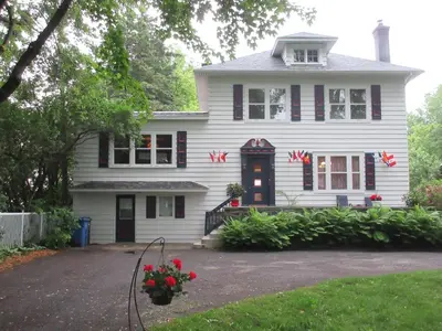 a white house with red flowers in front of it at Gîte Saint-Laurent in Trois-Rivières