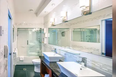 a white bathroom with two sinks and a toilet at Les Suites de Laviolette, an Ascend Collection Hotel in Trois-Rivières