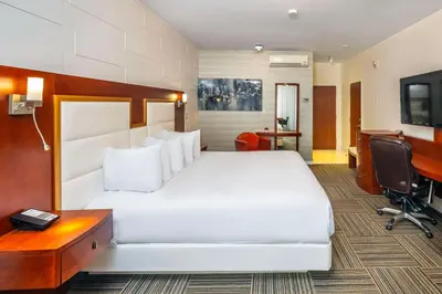 a bedroom with a large white bed and a desk at Les Suites de Laviolette, an Ascend Collection Hotel in Trois-Rivières
