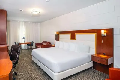 a bedroom with a large white bed and a desk at Les Suites de Laviolette, an Ascend Collection Hotel in Trois-Rivières